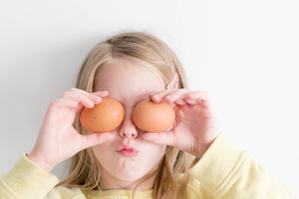 Young girl with eggs over eyes. Cooking with your kids is fun for you and them!